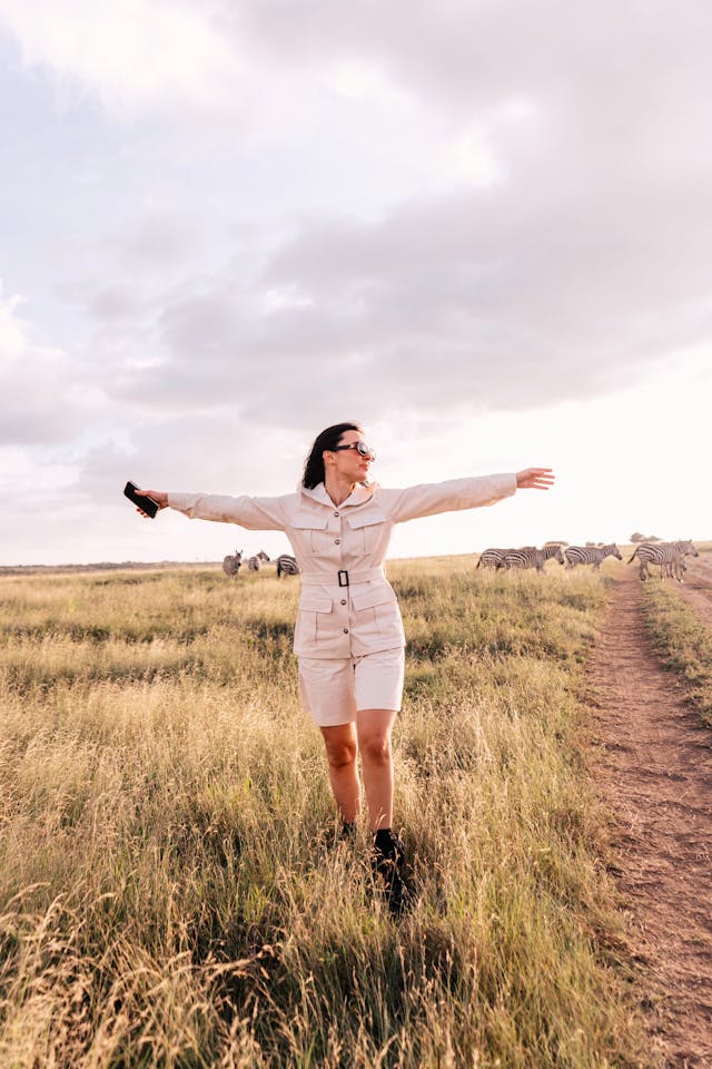 Woman in a safari romper walking through grass.