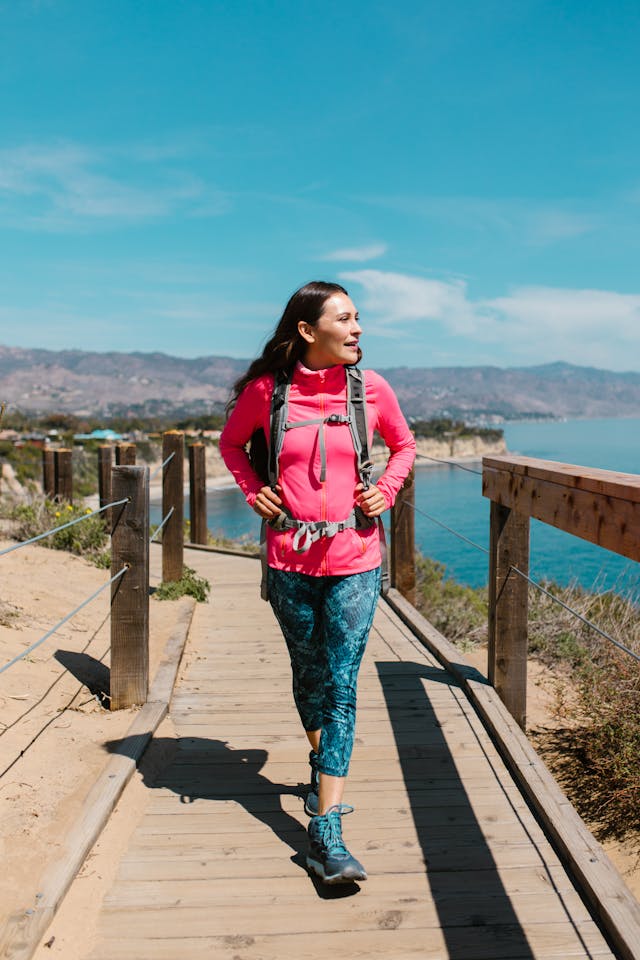 Woman hiking in colorful activewear by the coast in her sporty holiday outfit.