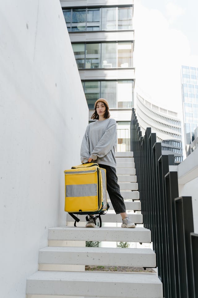 Woman in casual loungewear and beanie pulling a yellow bag—cozy city travel  have packed clothes for vacation.