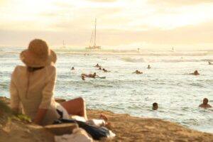 Women wearing hat sitting on a beach enjoying her vacation.